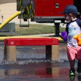 This youngster, two-year-old Beau Burglar, looks back on a sheet of falling water from the fire department's ladder truck.